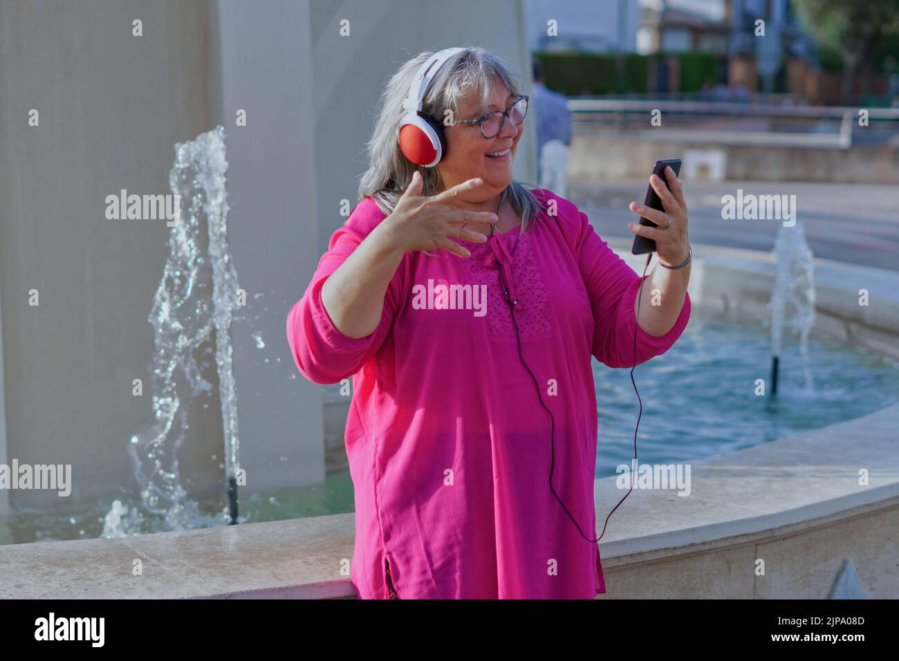 woman with white hair and glasses making a video call with her cell phone smiling Stock Photo