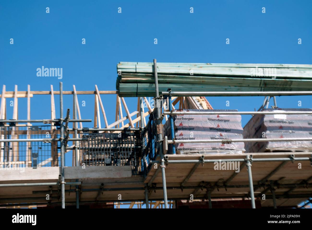 Roof of partially constructed house surrounded by scaffolding on building site Stock Photo
