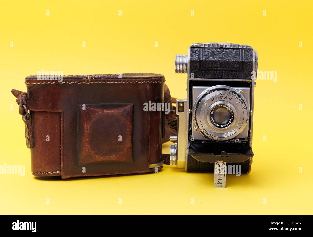 A vintage Camera from Kodak with old protective leather case isolated on a yellow background Stock Photo