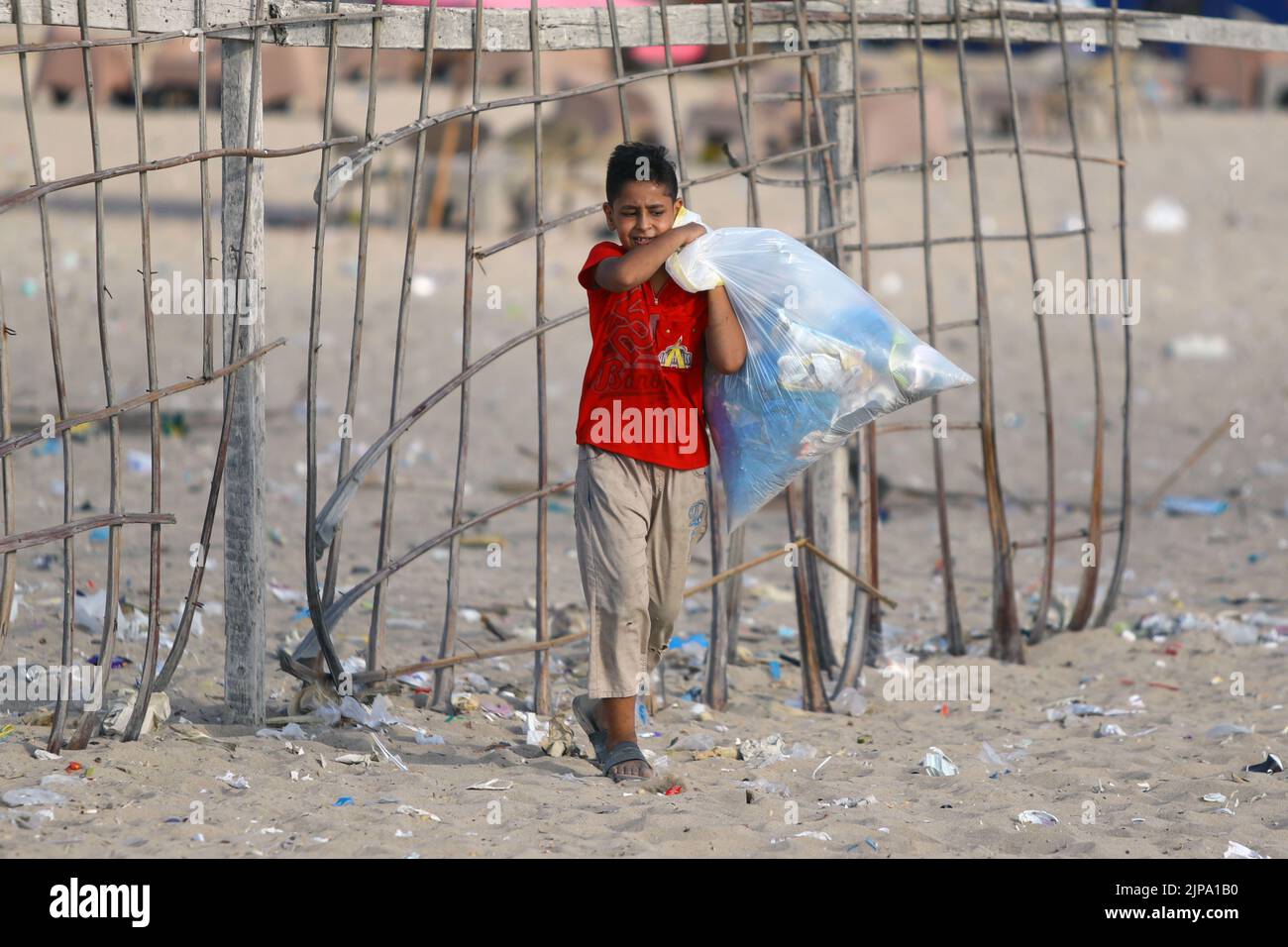 (220816) -- ALEXANDRIA, Aug. 16, 2022 (Xinhua) -- A child collects waste from the beach in Alexandria, Egypt, Aug. 13, 2022. On the beaches in the Egyptian city of Alexandria, a group of Egyptian young people are usually seen holding green and white plastic bags to collect the scattering waste. They are participants in a cleanup campaign organized by Banlastic Egypt, an environmental project launched by a group of youth in the Mediterranean city. The project seeks to raise the public's awareness of plastic pollution and how single-use plastic waste harms marine life if it eventually ends Stock Photo