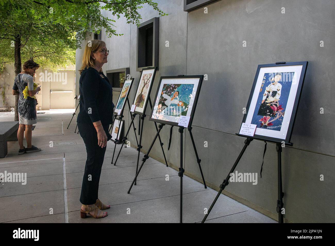 Dallas, USA. 14th Aug, 2022. A woman views paintings about 'comfort women' at an art exhibition marking the sixth International Memorial Day for 'Comfort Women' in Dallas, Texas, the United States, Aug. 14, 2022. Commemoration events including a film screening, an art exhibition, a peace and justice walk, and a candlelight vigil were held on Sunday to mark the sixth International Memorial Day for 'Comfort Women' in Dallas. TO GO WITH 'Feature: Unfinished story, unforgettable pain of WWII 'comfort women'' Credit: Xin Jin/Xinhua/Alamy Live News Stock Photo