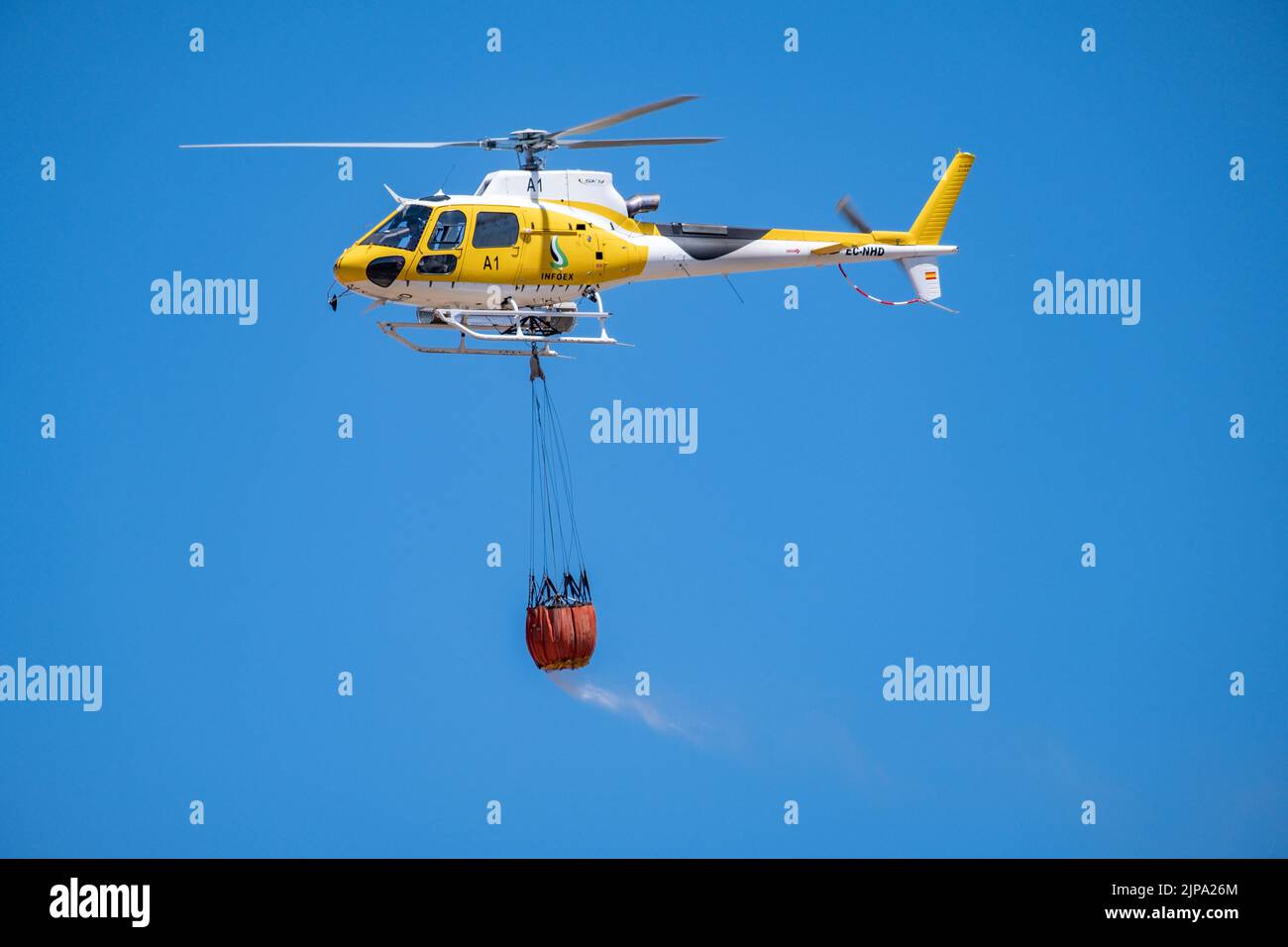 A firefighting service helicopter carrying a basket with water flying