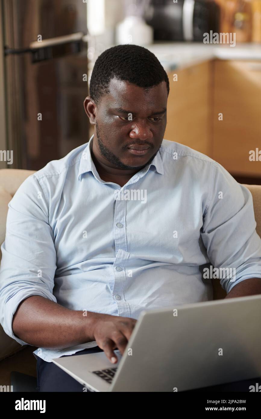 Serious Black software developer coding on laptop at home Stock Photo