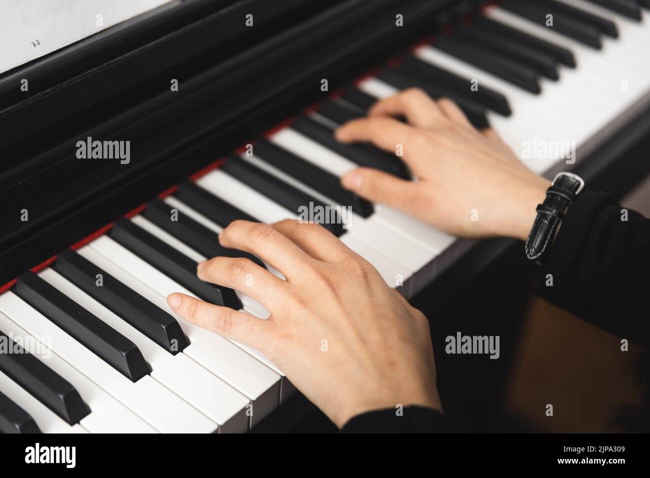 Close up of woman's hands playing piano by reading sheet music. Selective focus Stock Photo