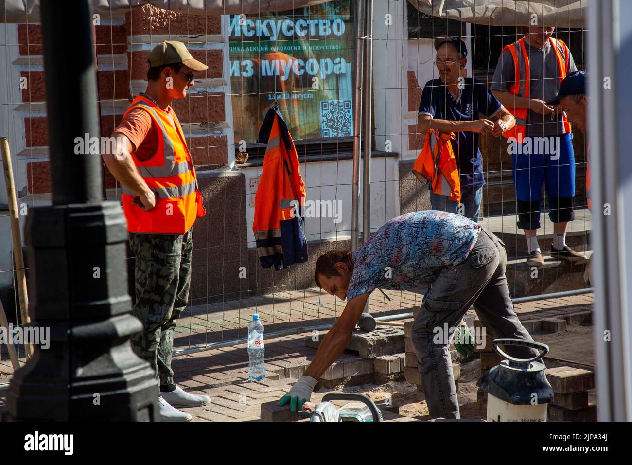 Moscow, Russia. 15th of August, 2022. Builders are working to replace paving slabs on Arbat Street in the center of Moscow, Russia. The electronic board reads 'Art from garbage' Stock Photo