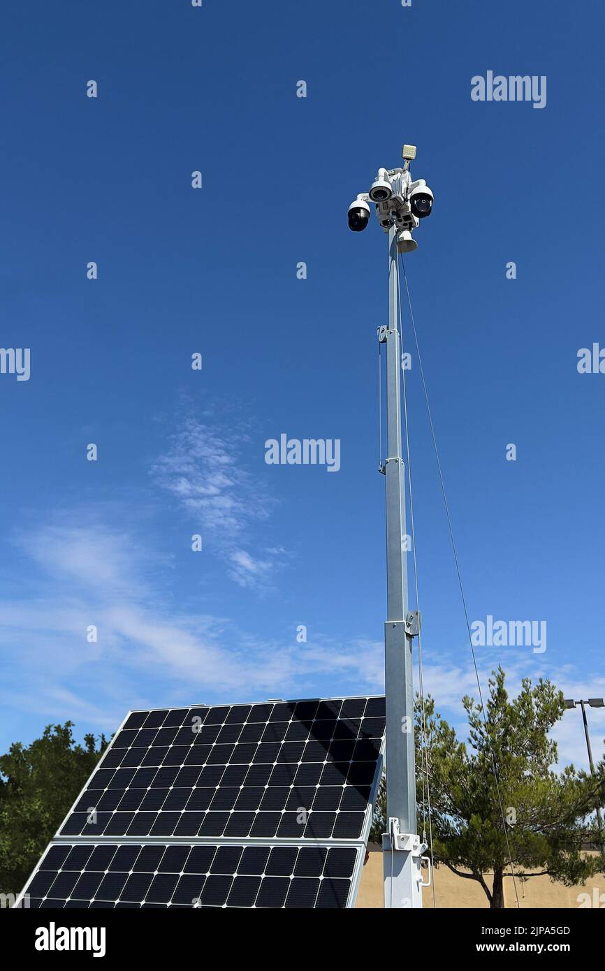 A CCTV mobile camera tower with a solar panel in a shopping center parking lot. Stock Photo