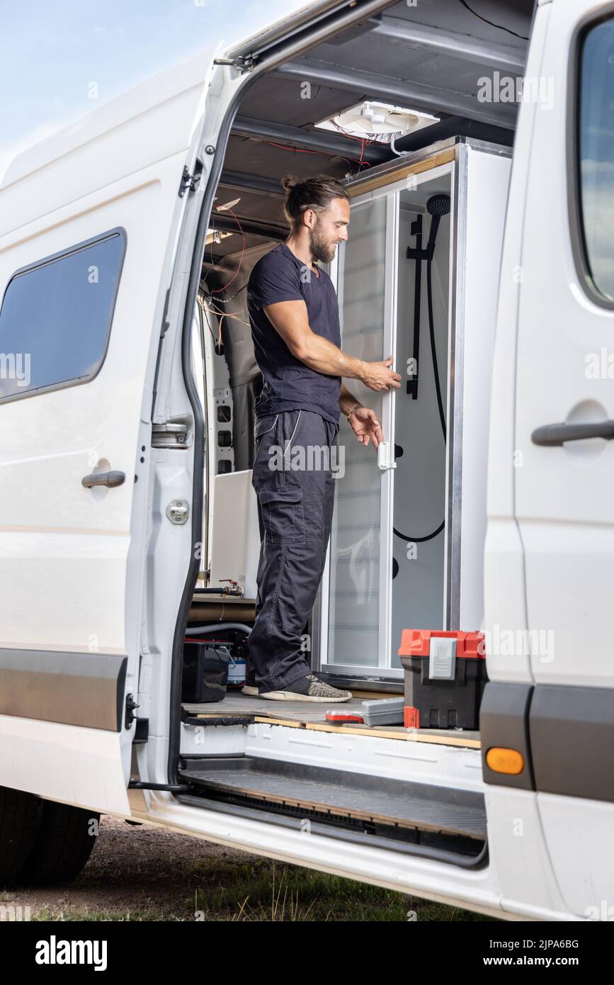 Man working on a shower room inside a camper van Stock Photo