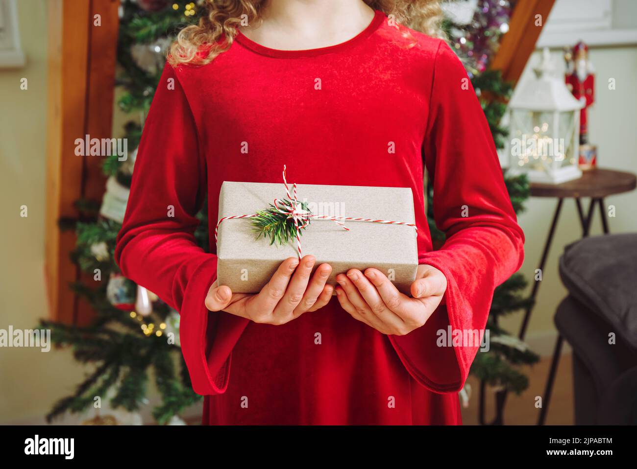 Close up view of girl child holding Christmas present in hands at home. Celebration. Stock Photo
