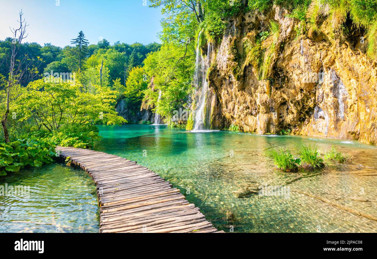 Wooden footpath at Plitvice national park, Croatia. Pathway in the forest near the lake and waterfall. Fresh beautiful nature, peaceful place. Famous Stock Photo