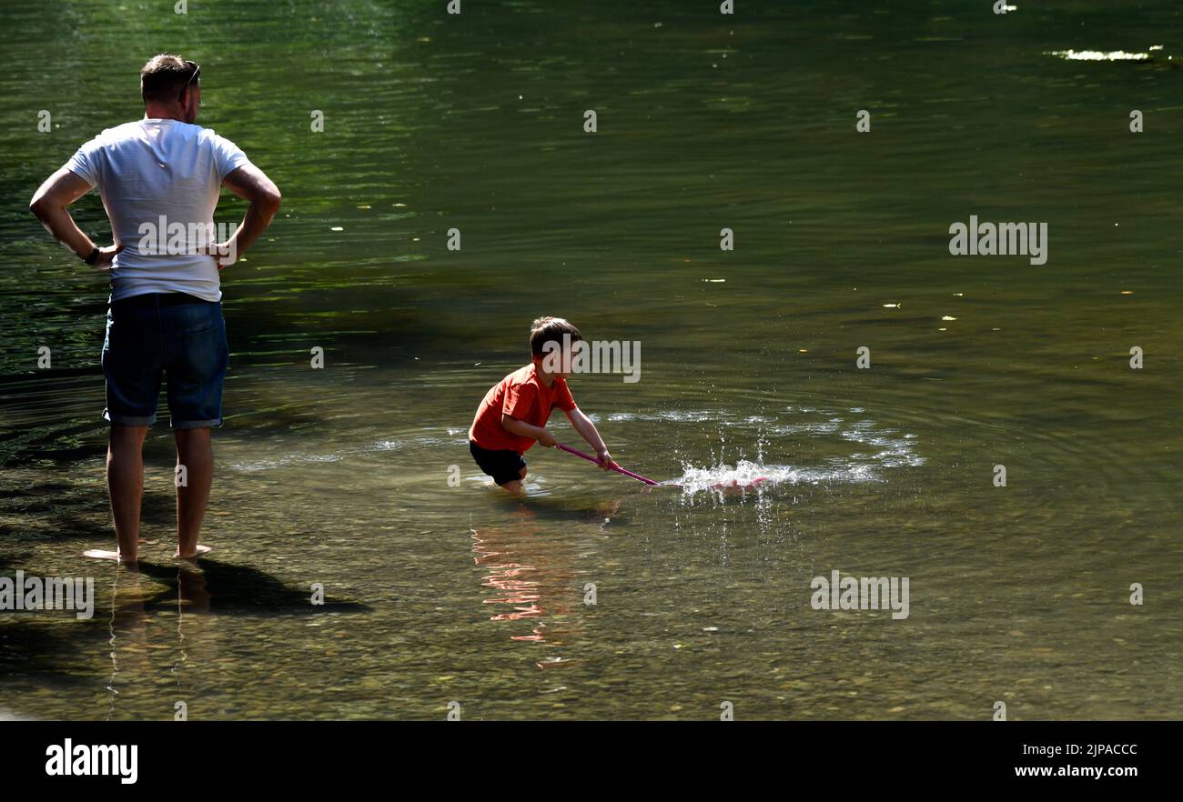 Parent watching child play in the waters River Teme near Dinham Bridge, Ludlow, Shropshire Stock Photo