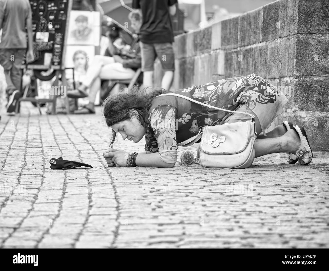 Prague, Czech Republic - June 2022: Homeless woman on the cobblestone streeets in the center of Prague, begging on his knees Stock Photo