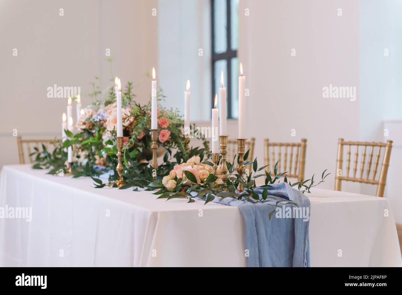 A wedding-style tablescape with a blue runner and elegant lit candles Stock Photo