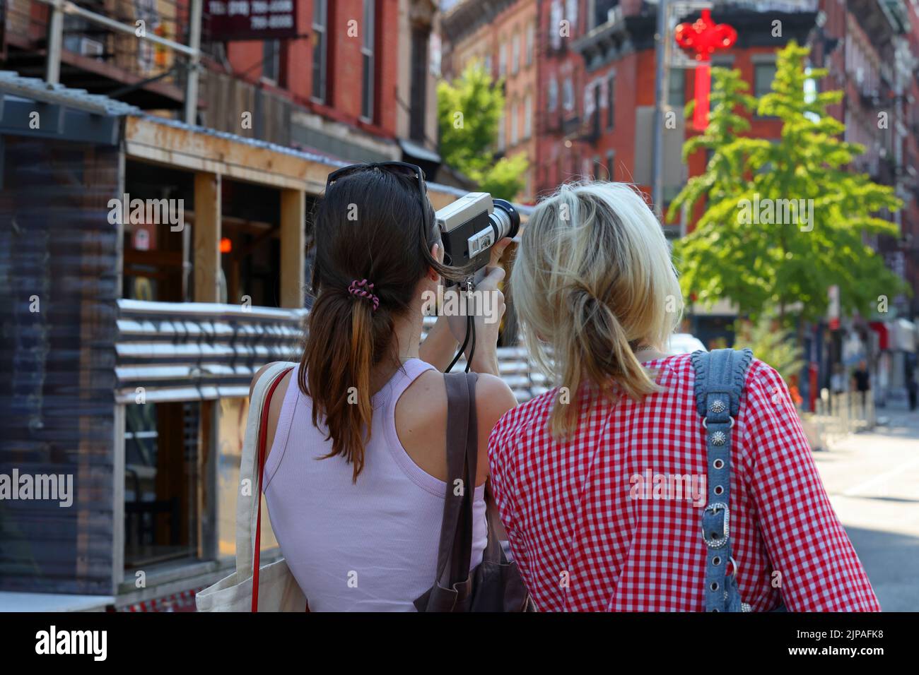 Woman indie filmmakers with a Canon Zoom 318 Super 8 film camera in Manhattan's 'Dimes Square' Chinatown/Lower East Side Stock Photo