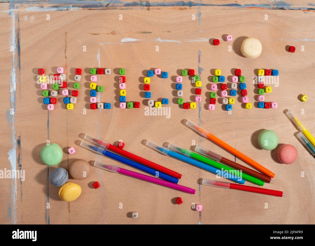 Number beads forming word Welcome, pencils and Macarons cookies on wooden desk. Back to school concept.  Stock Photo