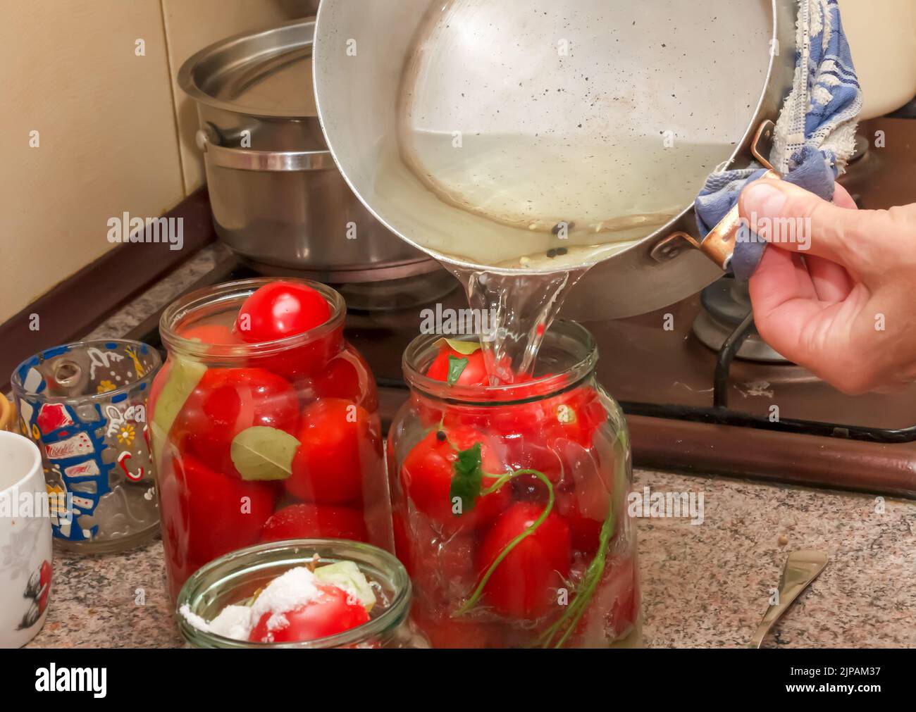 The process of preserving tomatoes for the winter. Women's hands pour