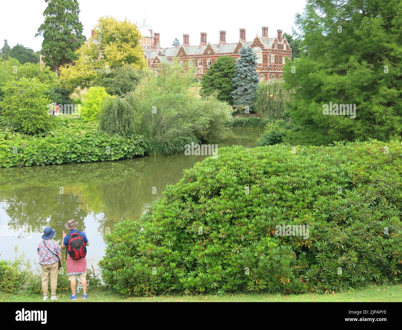 A visiting couple look across the lake towards the royal residence at Sandringham in Norfolk, the Queen's country retreat. Stock Photo