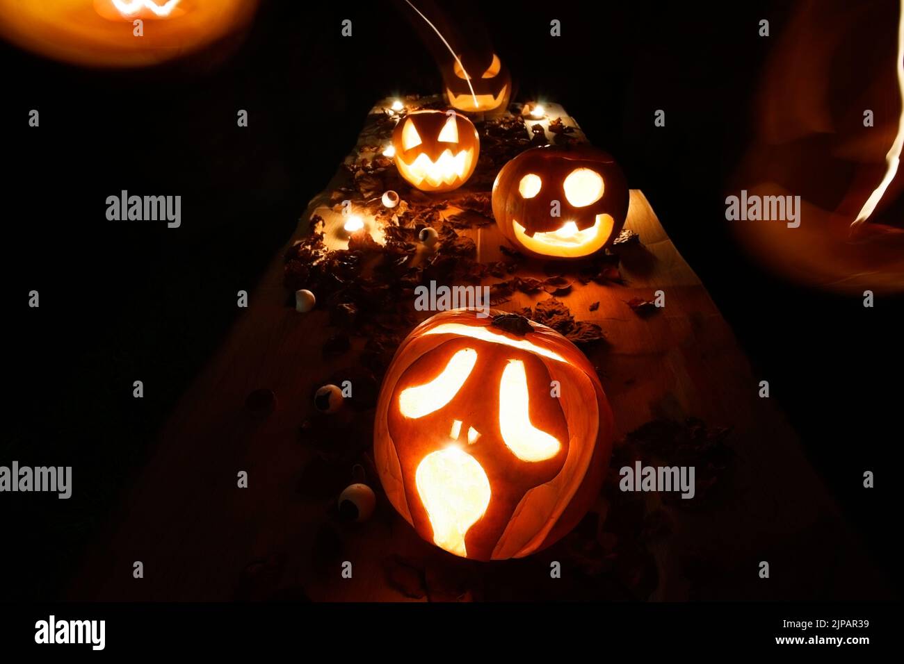 Scary Halloween pumpkins with eyes glowing inside at black background Stock Photo