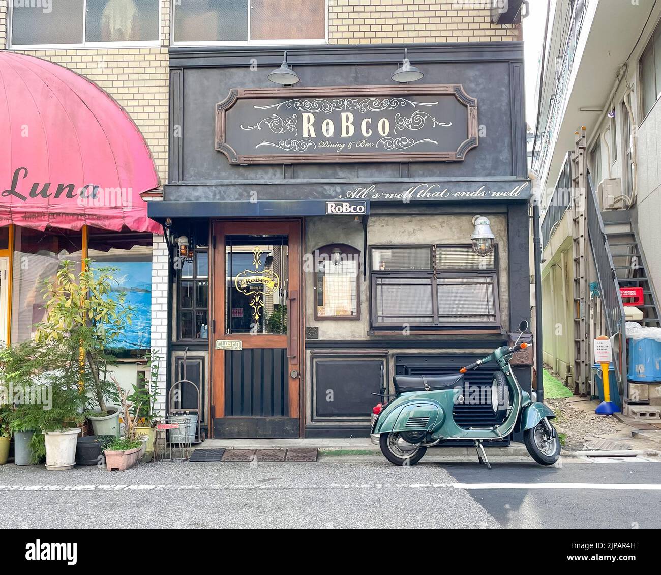 An exterior shot of  Robco Dinning Bar along a busy tourist street with a retro storefront and a blue scooter parked out front. Stock Photo