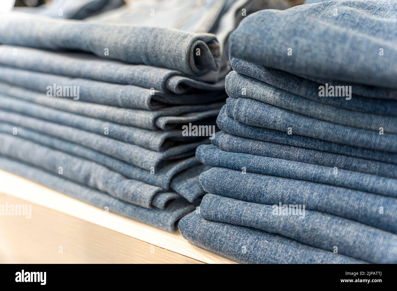 a stack of blue jeans on a shelf in the store. fashion clothing store