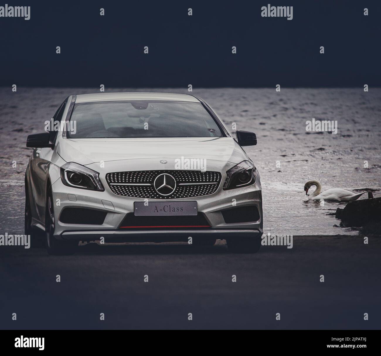 A luxury Mercedes Benz A class car parked on a shore of a lake Stock Photo