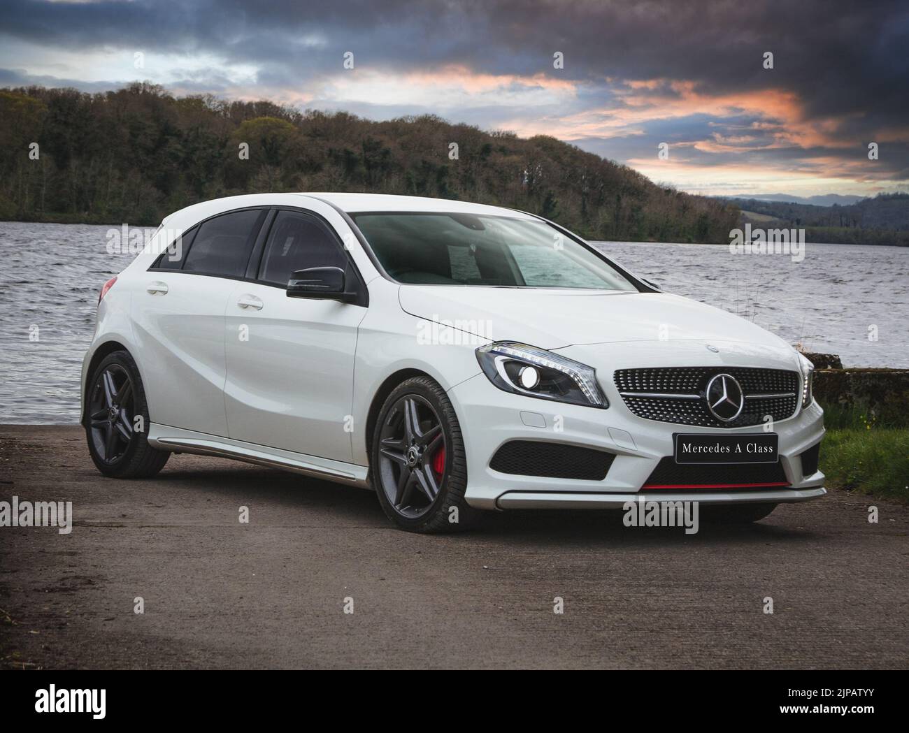 A luxury Mercedes Benz A class car parked on a shore of a lake Stock Photo