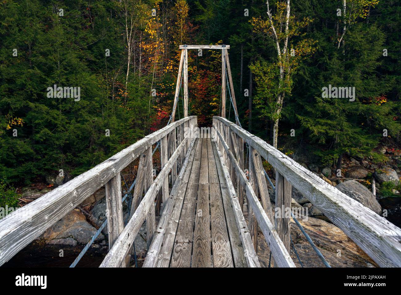 Hiking trail crosses the Ammonoosuc River via a wooden pedestrian bridge in the White Mountains of New Hampshire. Stock Photo