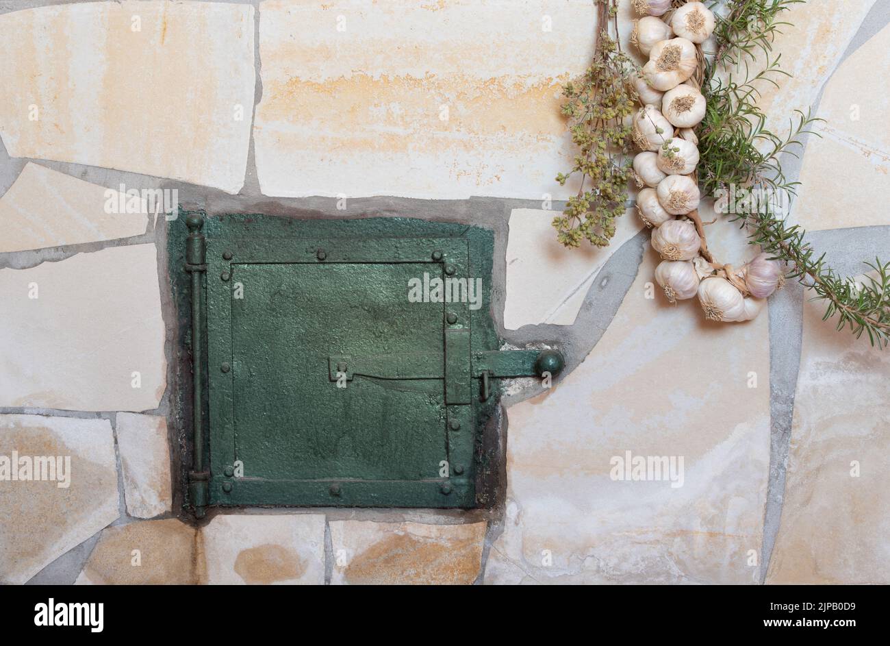 Background and closeup of a traditional oven with an oven door. Herbs and garlic hang down on