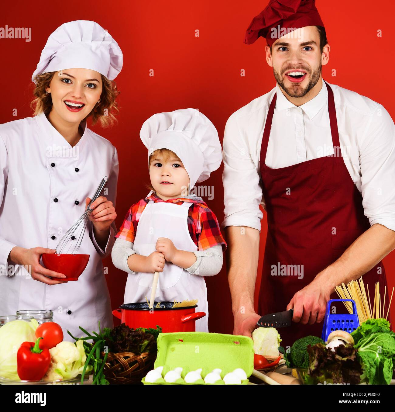 Happy family preparing healthy food in kitchen at home. Mother and father teach little son cooking. Stock Photo