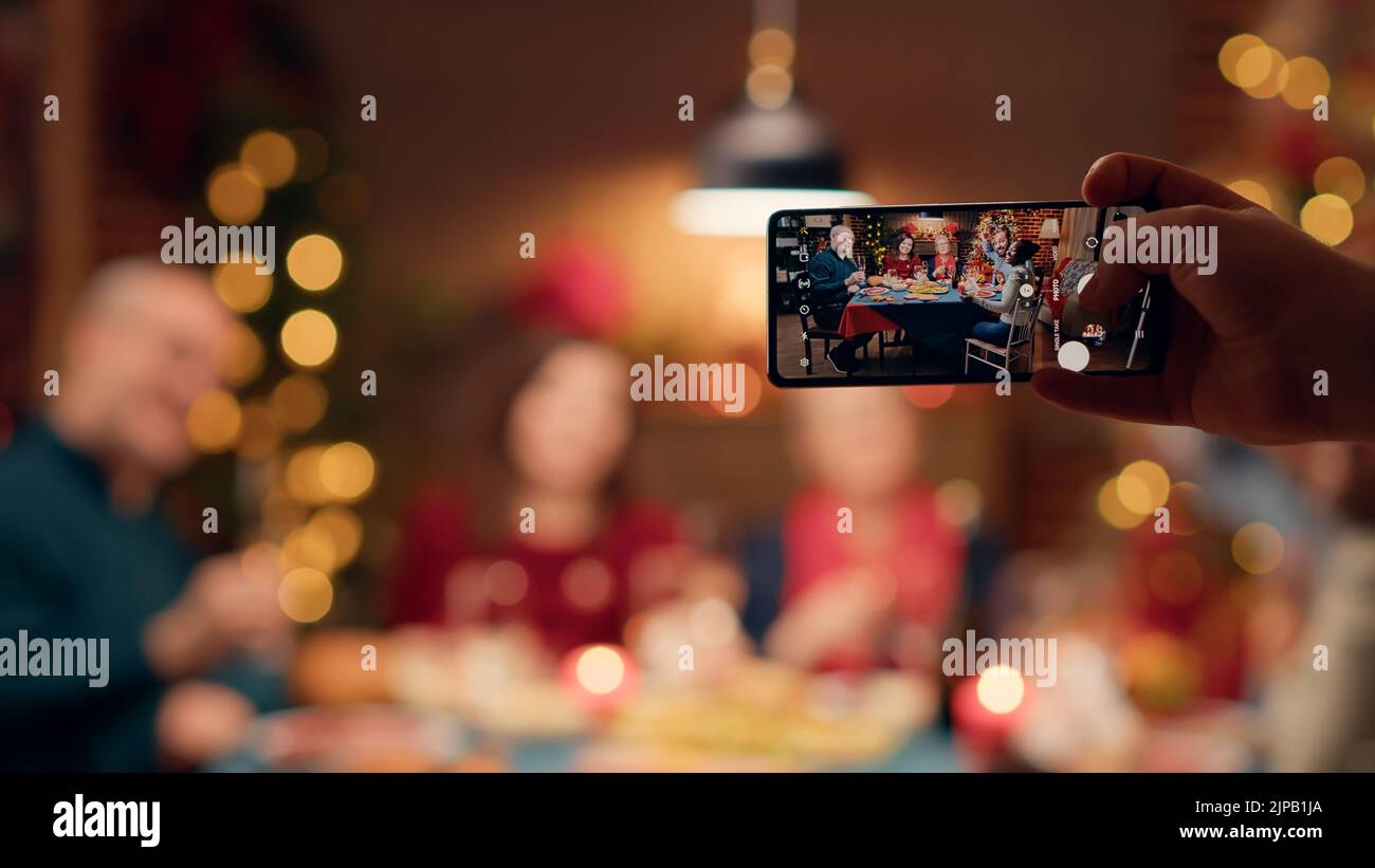 Festive family members getting photographed with smartphone while ...