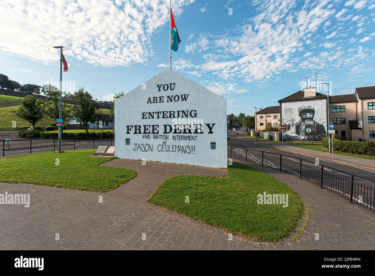Sign entering Free Derry with mural by Bogside Artists on side of house in Derry, Northern Ireland. Stock Photo