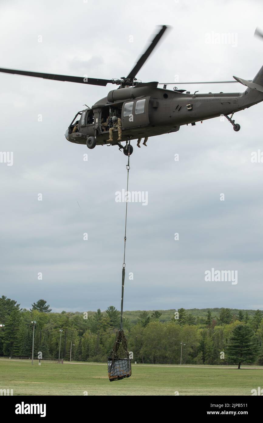 U.S. Army Soldiers, 237th Brigade Support Battalion, Cleveland, Ohio, attach a cable during a sling load mission at the Camp Grayling Parade Field, Grayling, Mich., Aug 14, 2022 during exercise Northern Strike 22-2. Northern Strike is designed to challenge approximately 7,400 service members with multiple forms of training that advance interoperability across multicomponent, multinational and interagency partners. (U.S. Army Photo by Sgt. Dustin Stewart). Stock Photo