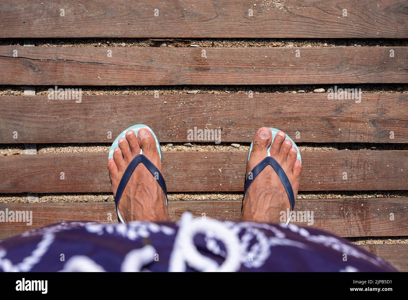 Mans feet in flip flops on wooden boardwalk. Top view. Flat lay. Empty space, for text or logo Stock Photo