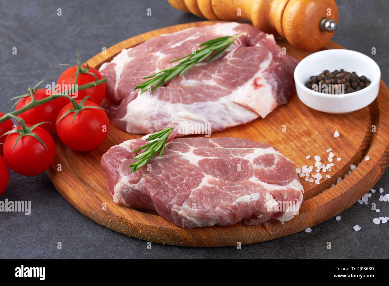 Raw meat with tomatoes on a black surface Stock Photo