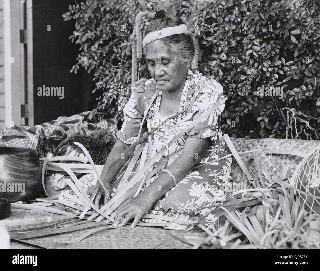 Black and white photograph of an elderly Hawaiian woman engaged in the traditional art of lauhala weaving using the  leaves of the hala (or pandanus) tree, Hawaii, USA Stock Photo