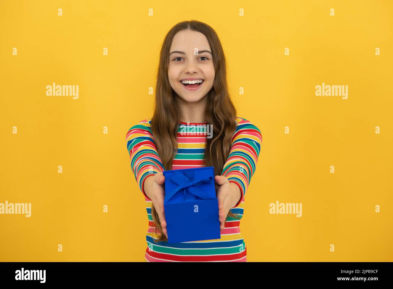 Portrait of teenager child girl 12, 13, 14, years old holding Christmas gift box. Teen giving birthday gift. Stock Photo