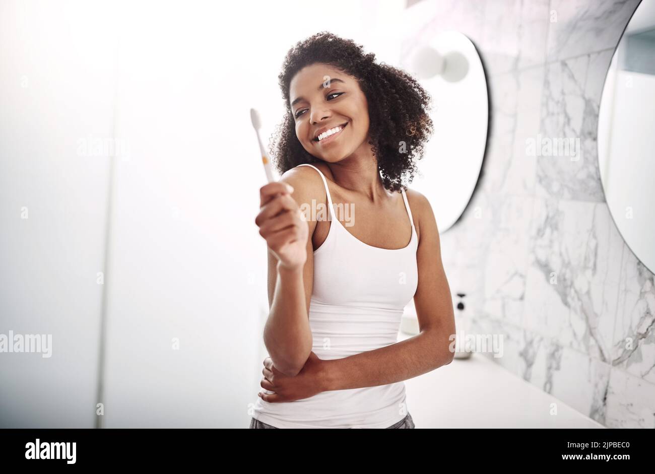 Now I have every reason to smile. Portrait of an attractive young woman brushing her teeth in the bathroom at home. Stock Photo