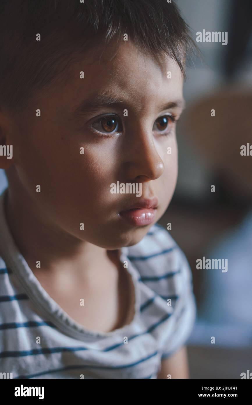 Close-up of a boy's face staring intently at something in the house. Childhood concept. Natural chang emotional state Stock Photo