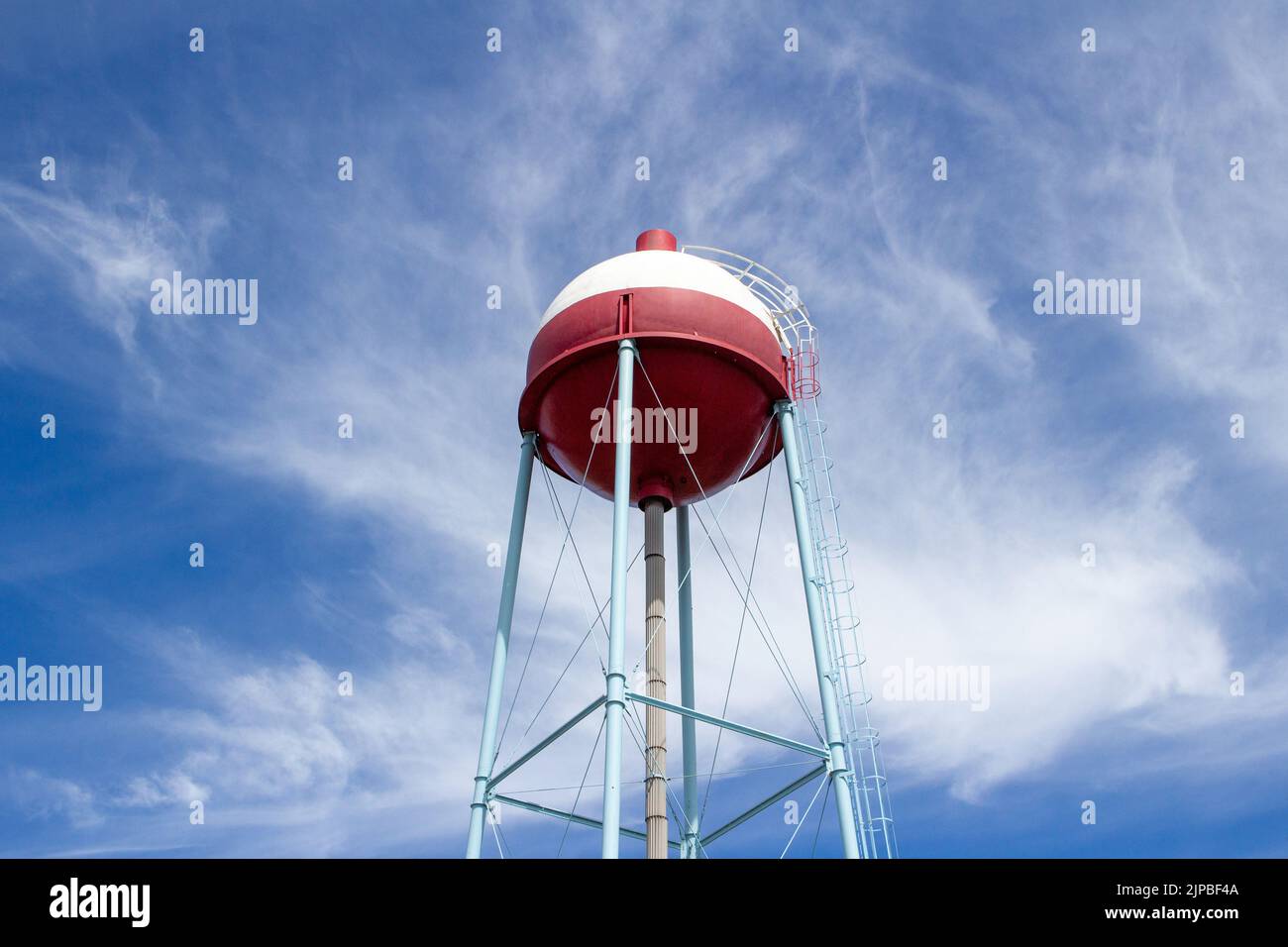 Upward view of a red and white round shaped water tower that resembles