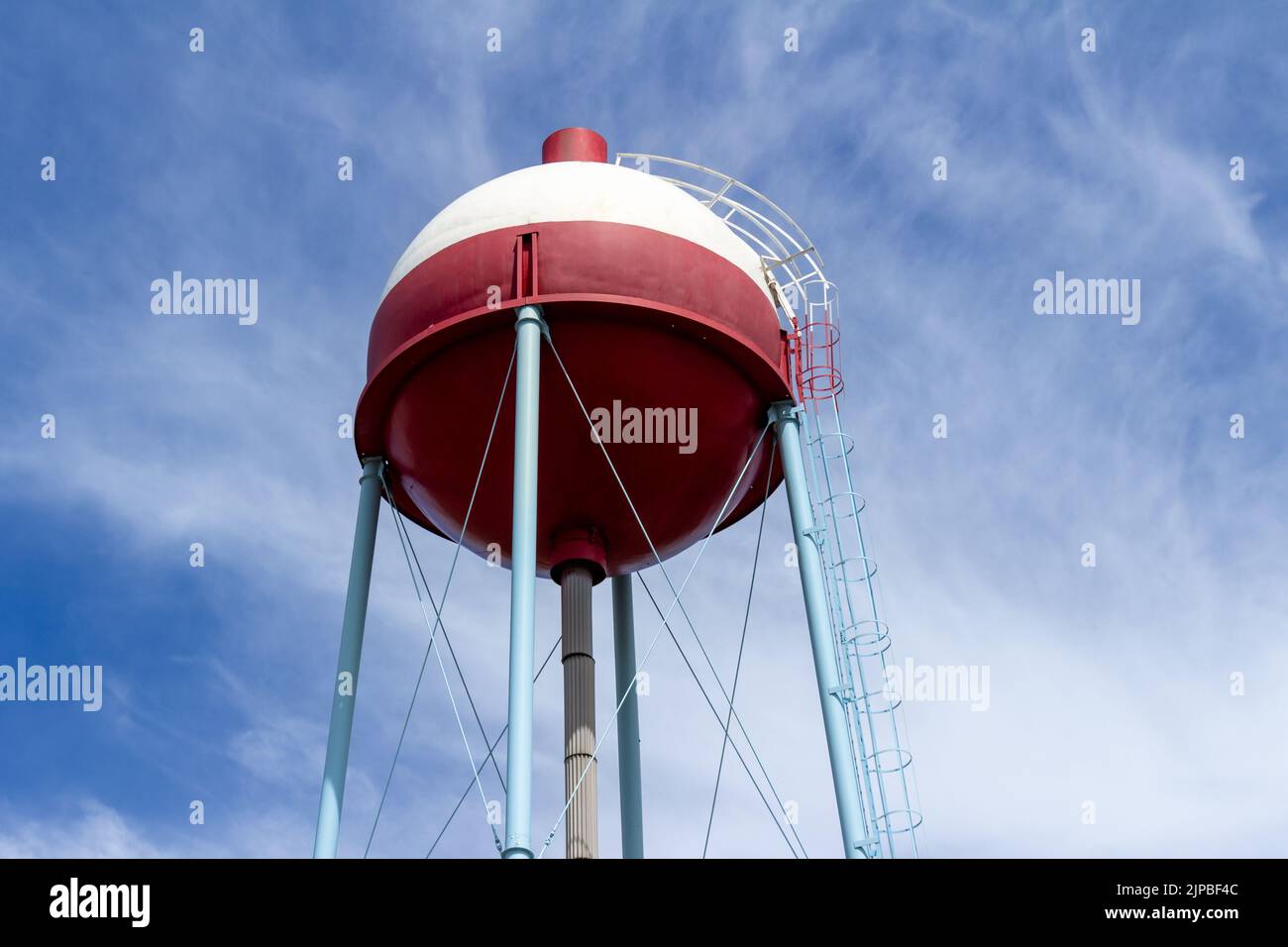 Upward view of a red and white round shaped water tower that resembles