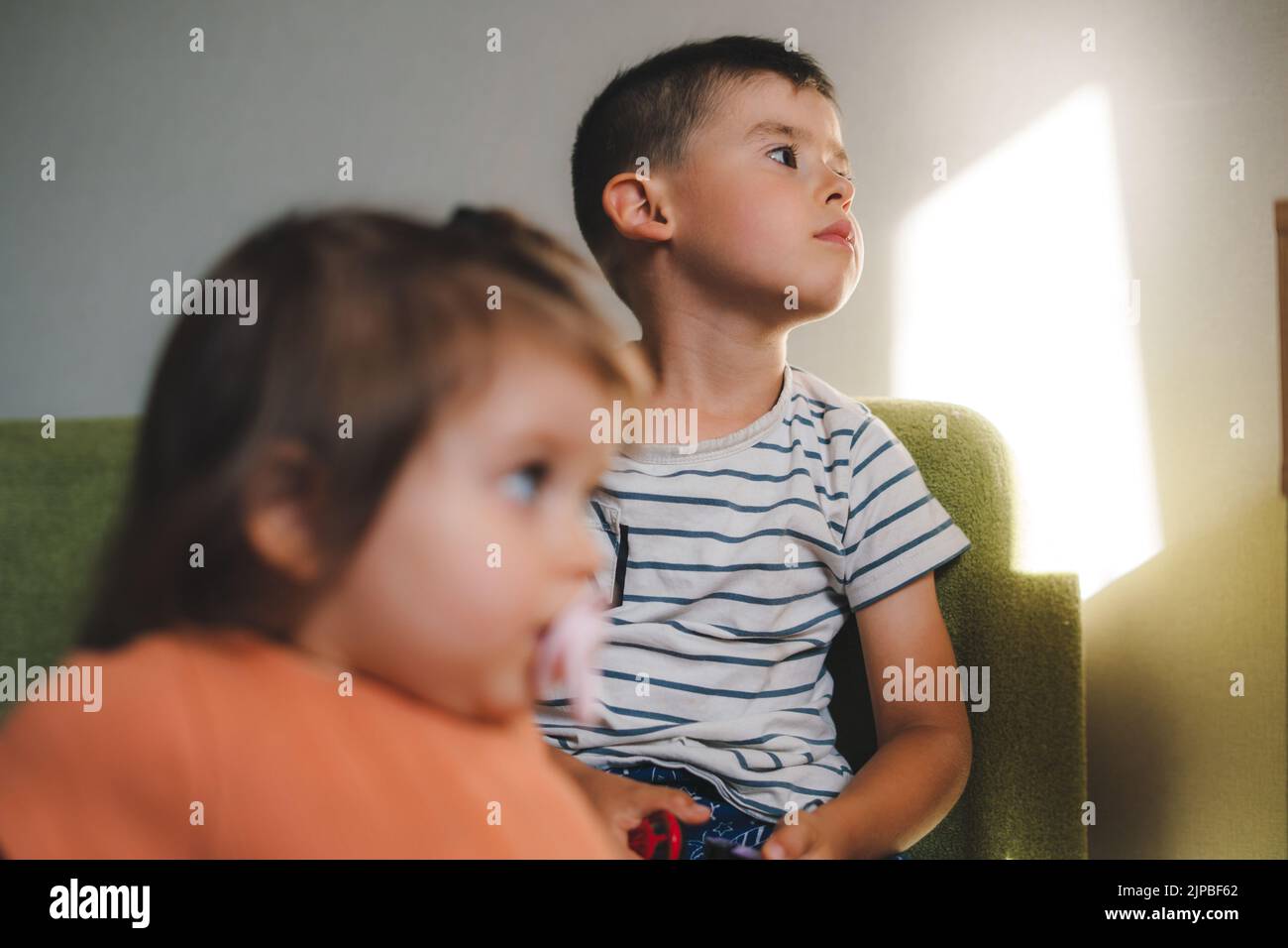 Caucasian brother spending time with his baby sister sucking a pacifier