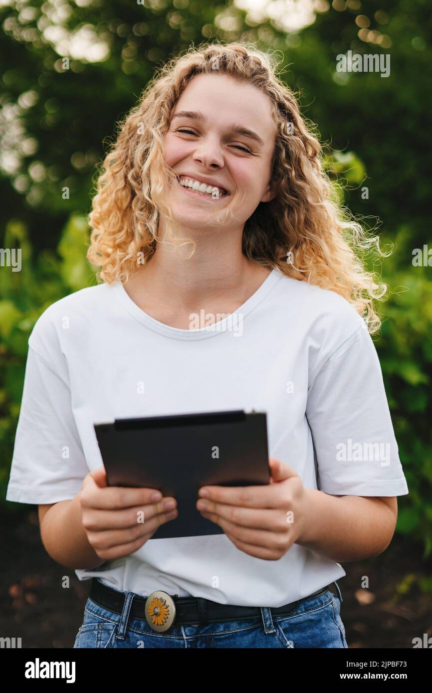 Employed woman portrait with curly hair smiling looking at camera, recording the growing of grapes in their fields on a tablet. Smart farming and Stock Photo