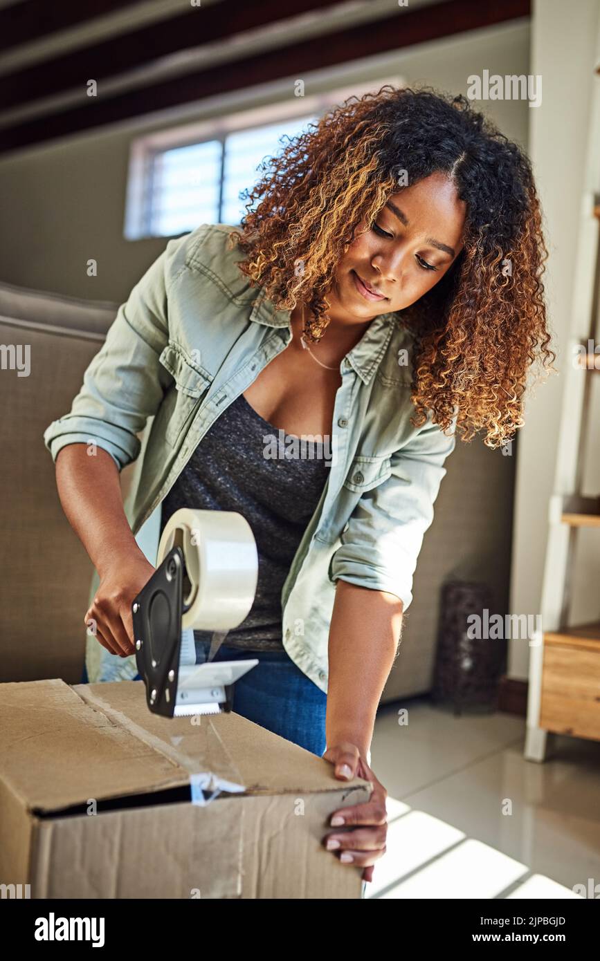 Im putting you away until I need you again. a confident young woman taping a box closed to put it away in storage after moving into a new home. Stock Photo