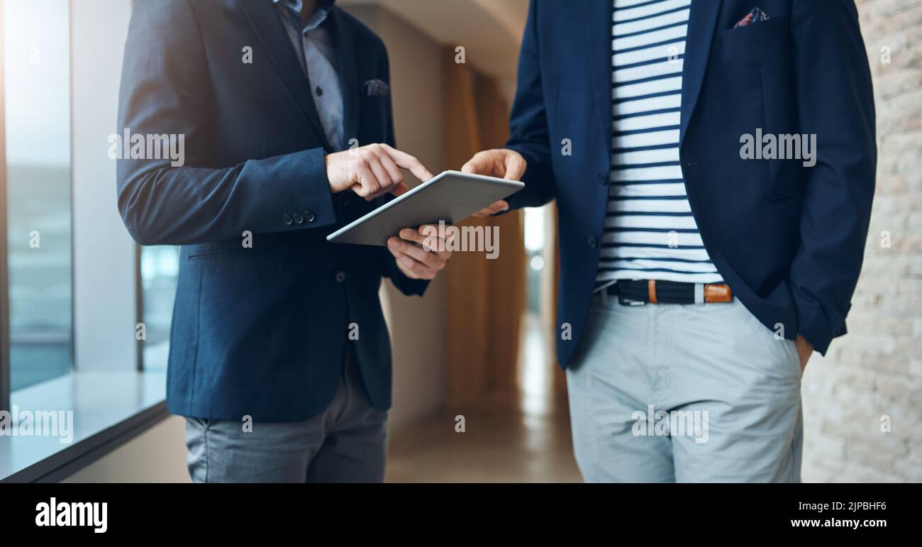 Using technology to smart moves. two businessmen using a digital tablet ...