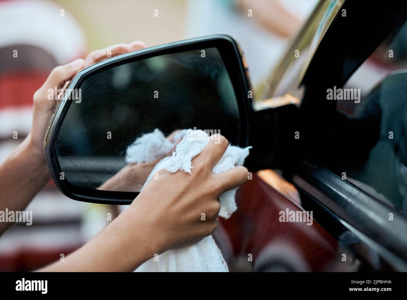 Now we can see in the mirror again. an unrecognizable young child washing their parents car outside during the day. Stock Photo