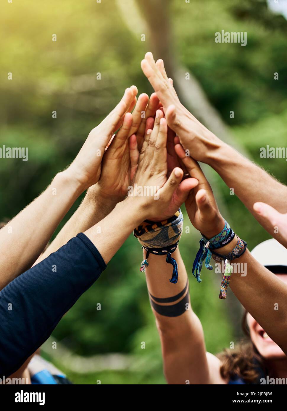 Lets go rafting. a group of unrecognizable peoples hands raised in the air to form a huddle together outside during the day. Stock Photo