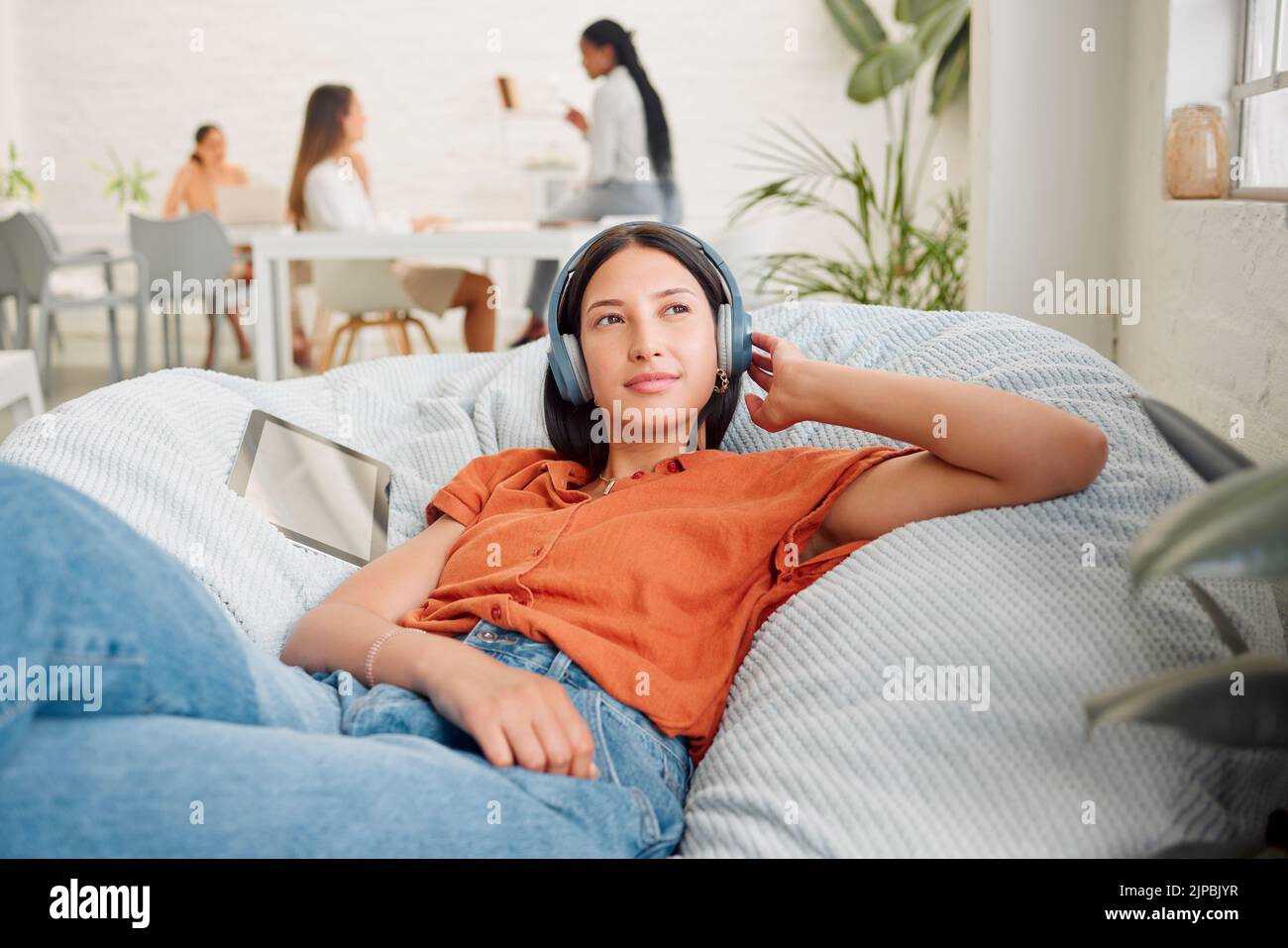 Creative wearing headphones, listening to music and relaxing with zen songs or podcast to help with thinking, planning and inspiration. Motivated Stock Photo