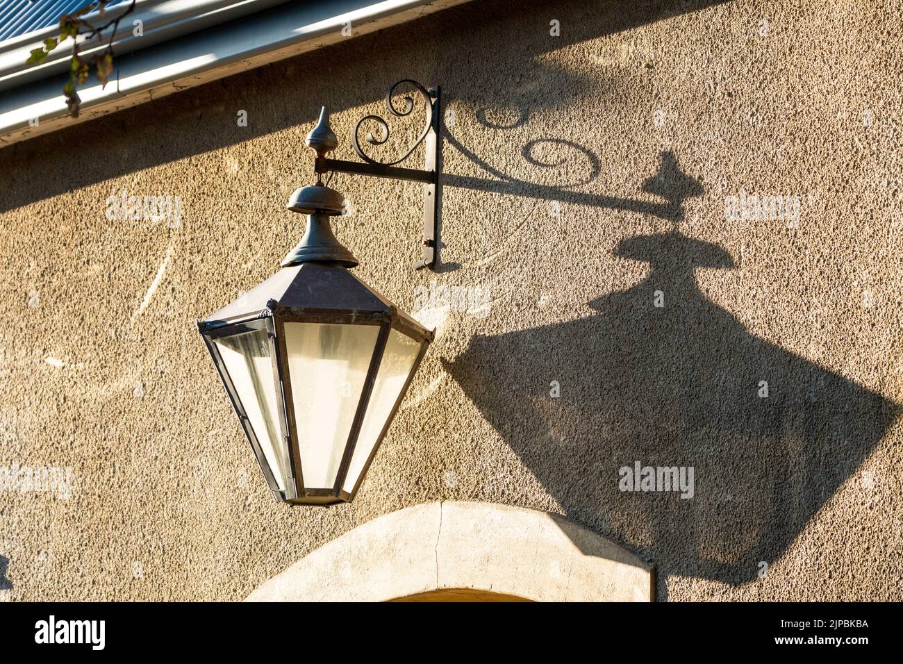 coach lamp close up on a wall surface with shadow showing architectural element and exterior decorative lighting Stock Photo