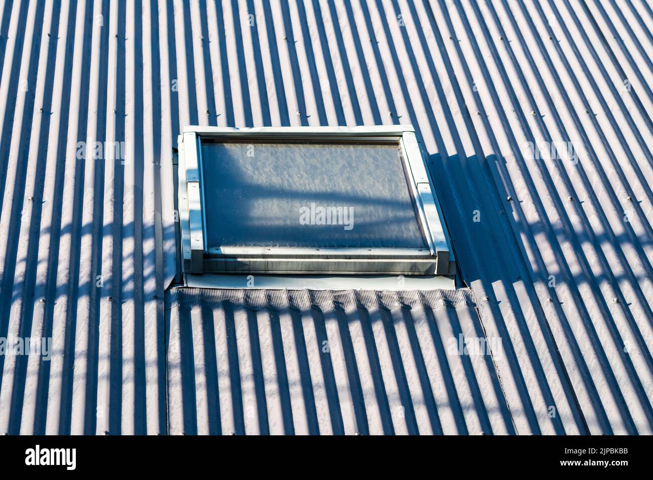 skylight or sky light window in a corrugated metal roof to let light in to a dark area of a building concept architectural element Stock Photo