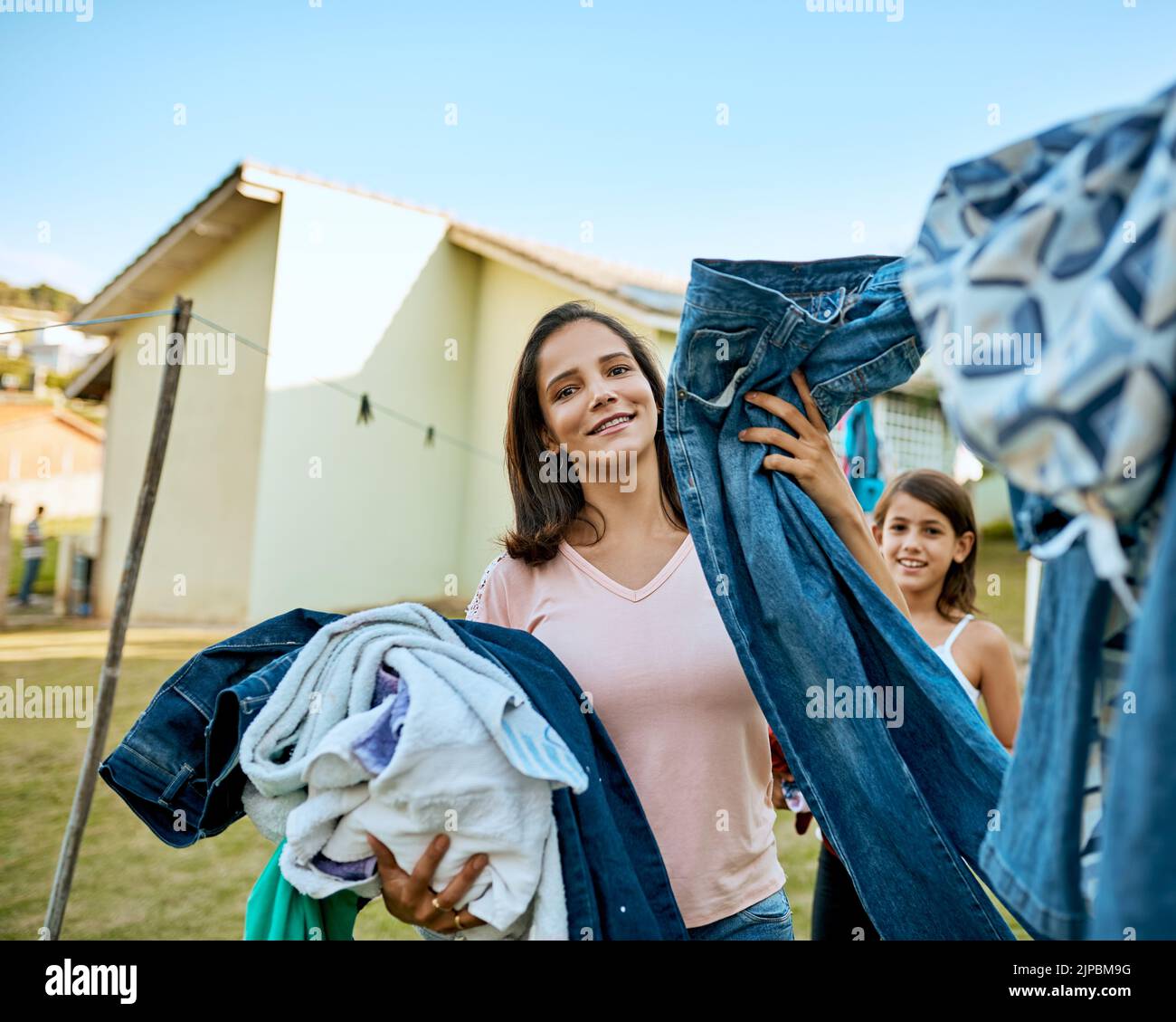 My family deserves clean clothes everyday. Portrait of a mother and daughter hanging up laundry together outside. Stock Photo