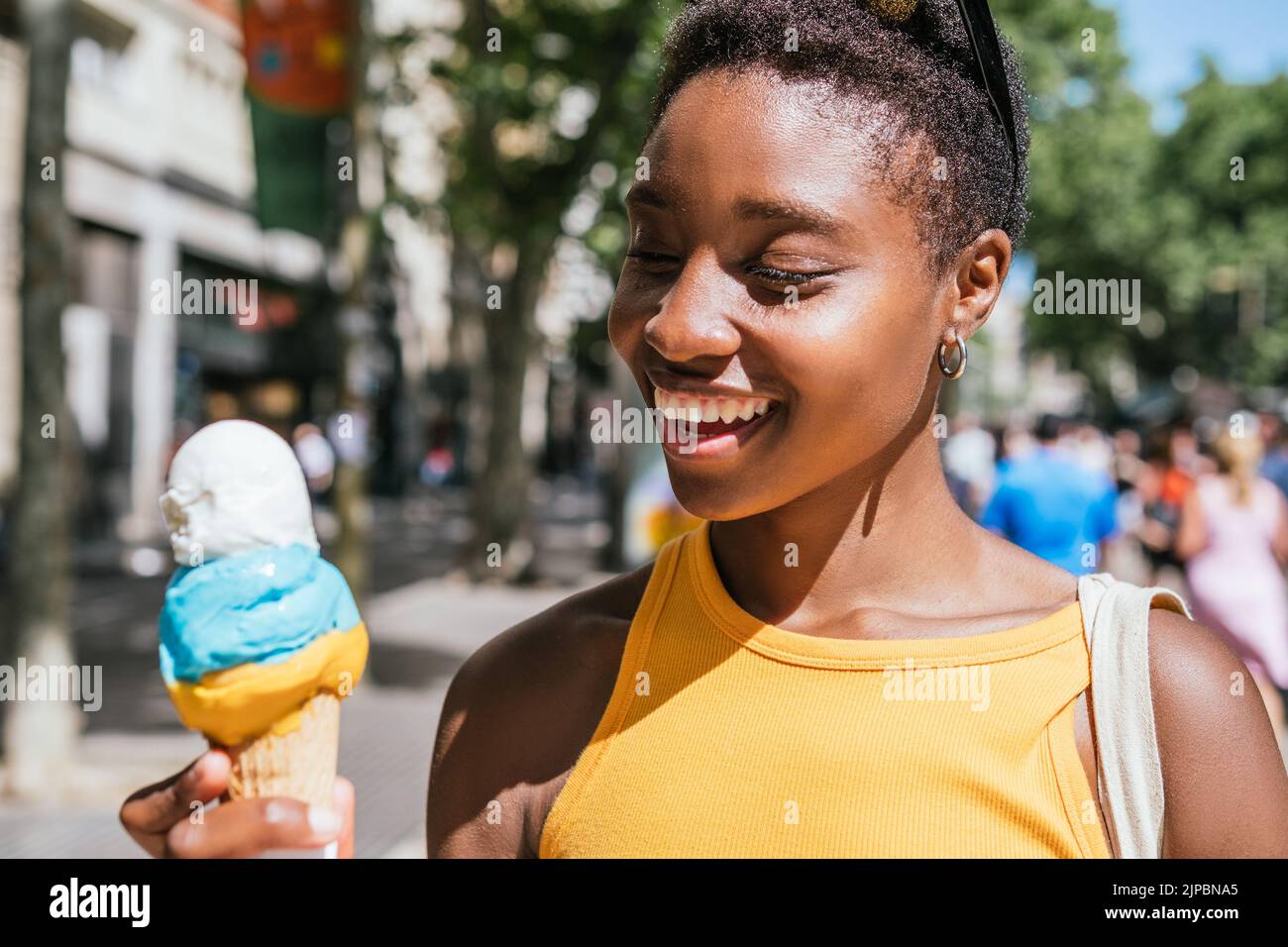 cheerful african american woman smiling while looking to her ice-cream on a summer day Stock Photo